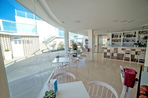 Un restaurante moderno con zona de bar, mesas al aire libre y vistas a la ciudad.