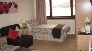 A bedroom with two beds, a nightstand, a lamp, a telephone, and a window with a view of the outdoors. - Stronchreggan View Guest House (Fort William)