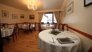 A dining area with round tables, chairs, and a chandelier. - Stronchreggan View Guest House (Fort William)
