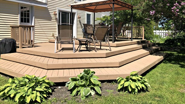 Eine überdachte Terrasse mit Gartenmöbeln und einem Grill.
