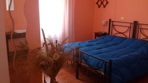 A bedroom with a bed, a nightstand, and a vase with dried plants. - Il Piccolo Paradiso (Livorno)