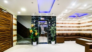 A lobby with a reception desk, a staircase, and a seating area.