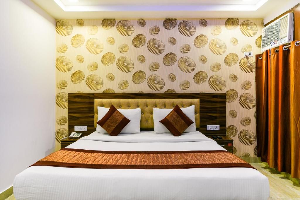 Een hotelkamer met een groot bed, een hoofdeinde, een nachtkastje en een muur met een decoratief patroon.