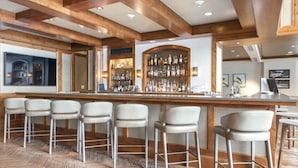 A bar area with wooden beams, a bar counter, and multiple stools.