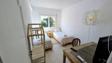 Un dormitorio con dos camas individuales, una escalera de madera, un escritorio con ordenador y una lámpara decorativa.