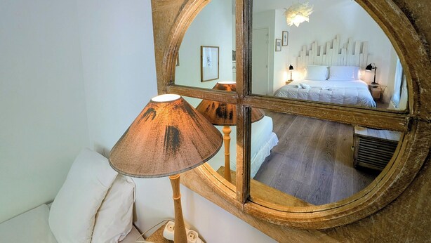 Ein Zimmer mit einem großen Spiegel, der ein Bett und eine Lampe widerspiegelt.