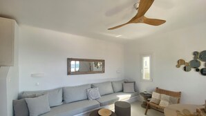 Un salon moderne avec un canapé gris, une table basse ronde en verre et un ventilateur de plafond.