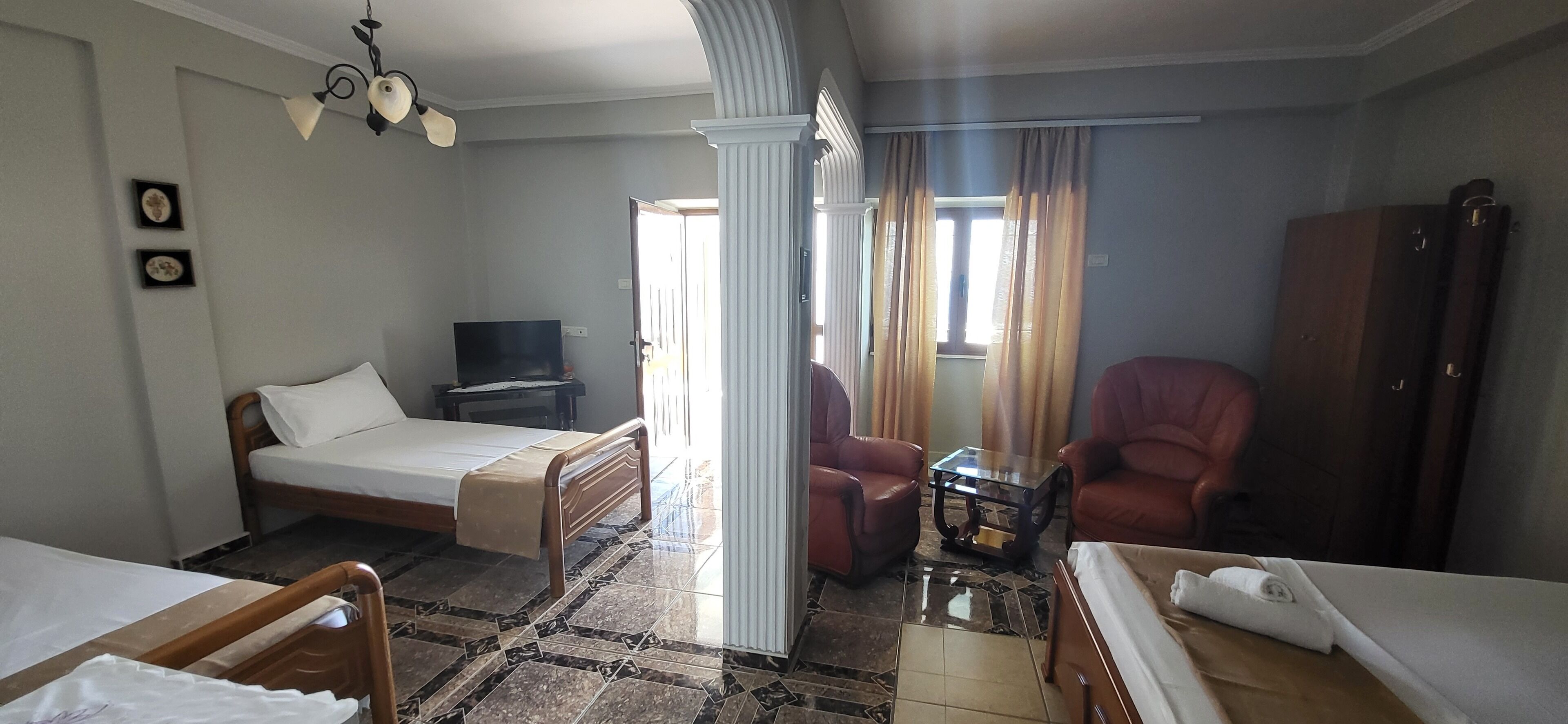 A hotel room with a bed, a desk, a chair, a television, and a wardrobe.