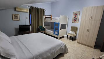Une chambre d’hôtel comprenant un grand lit, un bureau avec une chaise, un lit superposé, une armoire et un téléviseur.