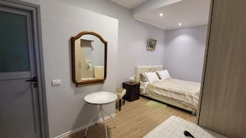 Un dormitorio con una cama, una mesita de noche, una silla, un espejo y una puerta.