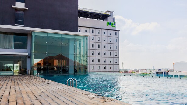 Een modern hotel met een glazen gevel, een zwembad en een dakbostuin.
