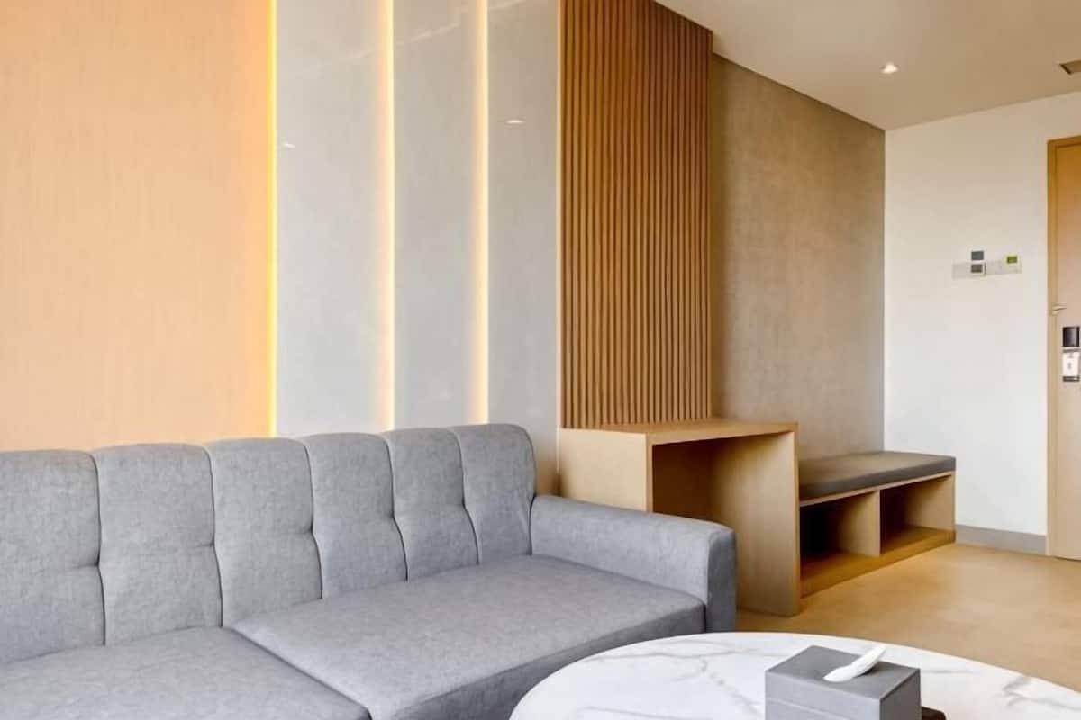 A modern reception area with a grey sofa, a wooden bench, and a marble table.