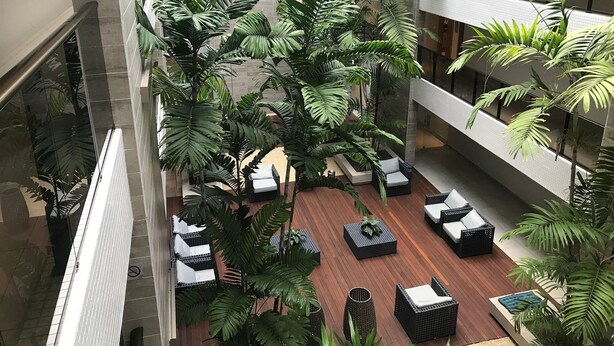 Un atrium à plusieurs niveaux, agrémenté de plantes d’intérieur, de coins salon et doté d’une architecture moderne.