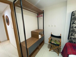 Quarto compacto com cama, escrivaninha dobrável, cadeira e guarda-roupa.