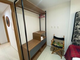 A compact room with a bed, a foldable desk, a chair, and a wardrobe.