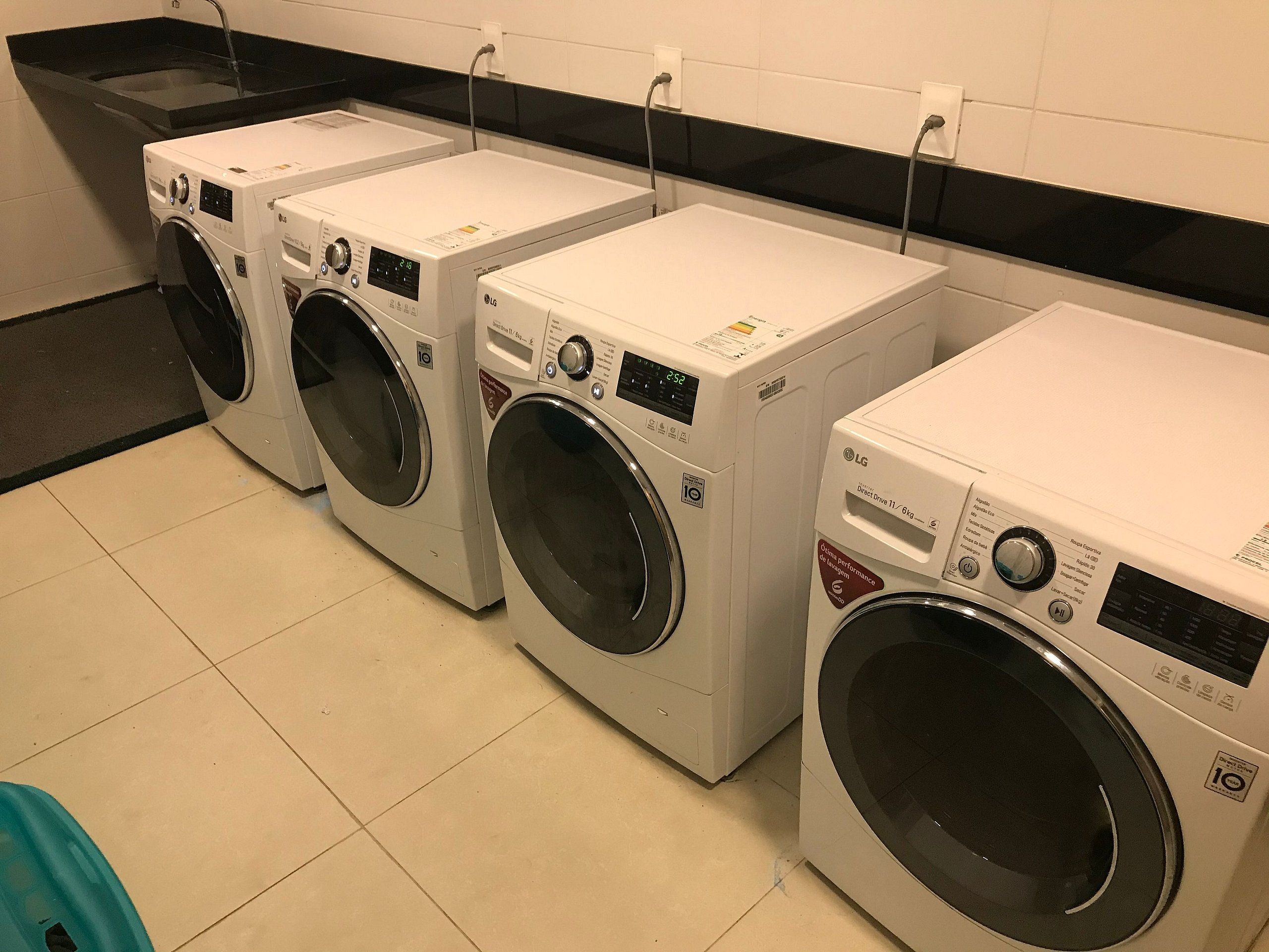 A row of white front-loading washers in a commercial setting.