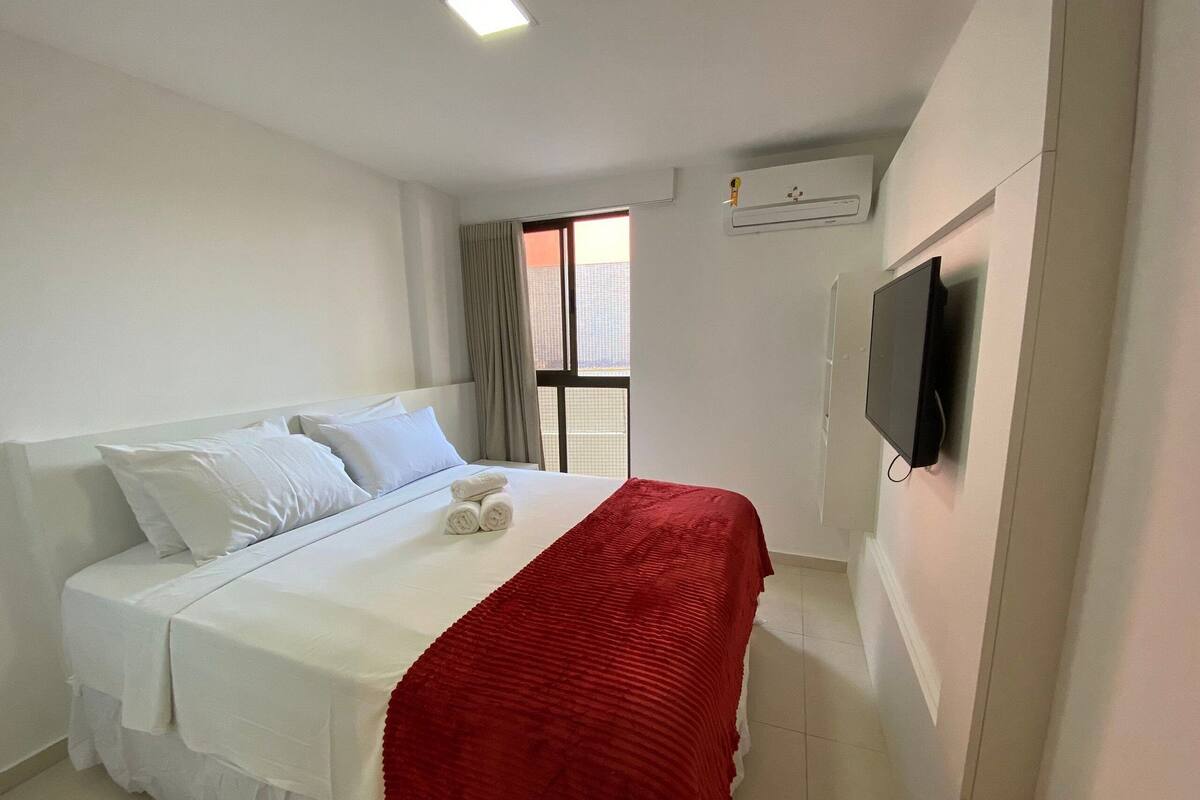 Una habitación de hotel con una cama, un televisor y una ventana.