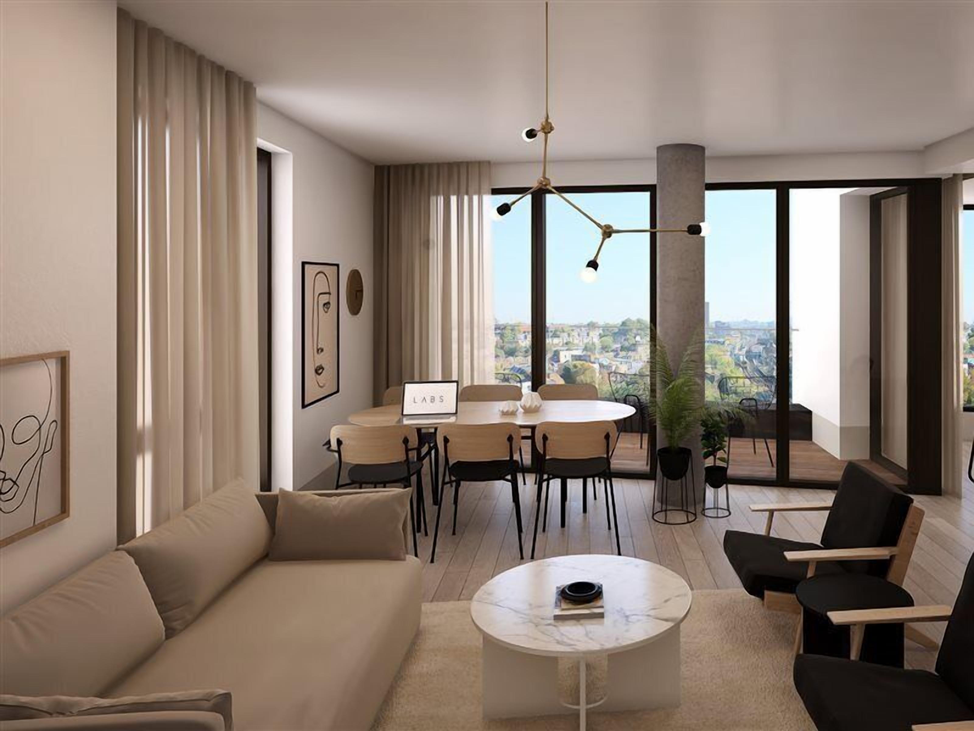 A modern living room with a sofa, a coffee table, and a dining area with a table and chairs. There is a large window with a view of the city.