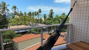 Una hamaca en un balcón con vistas a la playa y palmeras.
