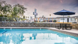 Une piscine bordée d’un mur en pierre et un panneau indiquant l’hôtel Sea Rock Inn.
