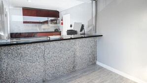 Une cuisine moderne dotée de plans de travail en granit, d’une hotte de cuisson en acier inoxydable et offrant une vue sur la salle à manger adjacente.