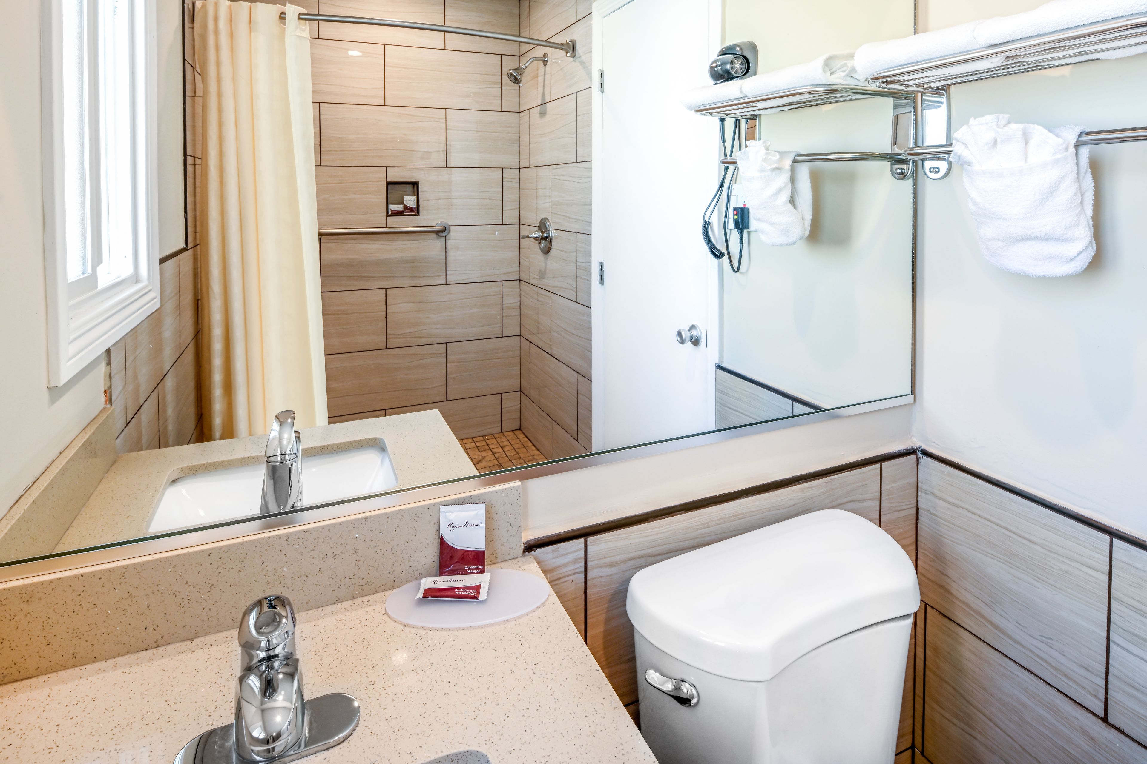 A modern bathroom with a glass shower enclosure, a white toilet, a sink with a faucet, and a towel rack.