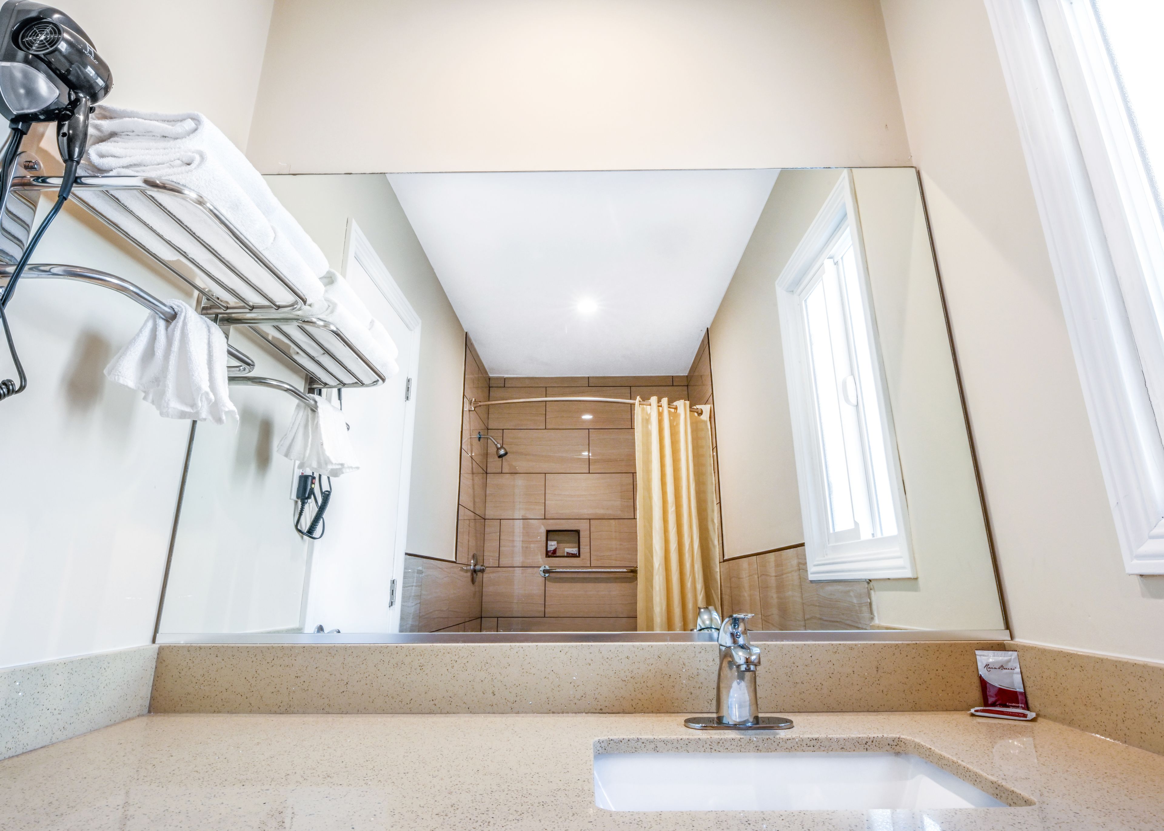 Un baño moderno con un espejo grande, un lavamanos y una zona de ducha.