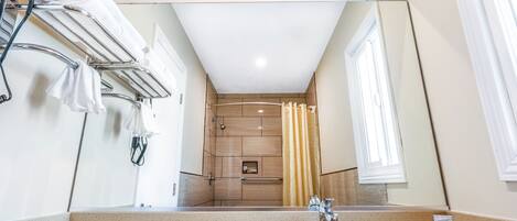 Un baño moderno con un espejo grande, un lavamanos y una zona de ducha.