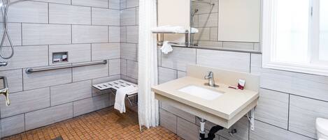 A modern bathroom with a shower, a sink, a towel rack, and a mirror.