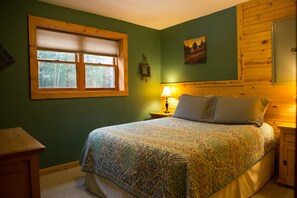 Een slaapkamer met een bed, een raam, een lamp en een foto aan de muur.