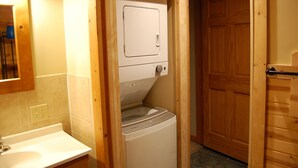 A laundry room with a washing machine and dryer, wooden door, and a sink with a mirror above it.