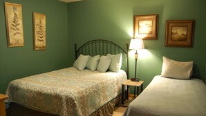A bedroom with a bed, bedside table, lamp, and two framed pictures on the wall.