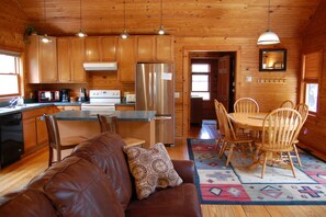 L’intérieur d’un chalet en bois comprend une cuisine, un coin repas et un salon.
