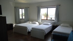 A hotel room with two single beds, a small desk, a chair, and a window with curtains. - Arpini Hotel (Rio Grande)