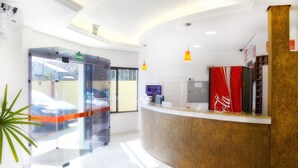 A reception area with a curved counter, a Coca-Cola refrigerator, and a glass door entrance. - Arpini Hotel (Rio Grande)