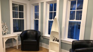 A room with a black leather chair, a white shelf with a bicycle, and a ship's wheel decoration. - Location, Location, Location! Downtown Newport! Newly Renovated (Newport)