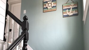 A staircase with white and black balusters, a wooden handrail, and a light blue wall with two nautical-themed wall hangings. - Location, Location, Location! Downtown Newport! Newly Renovated (Newport)