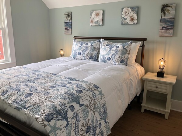 A bedroom with a bed, nightstands, and wall art.