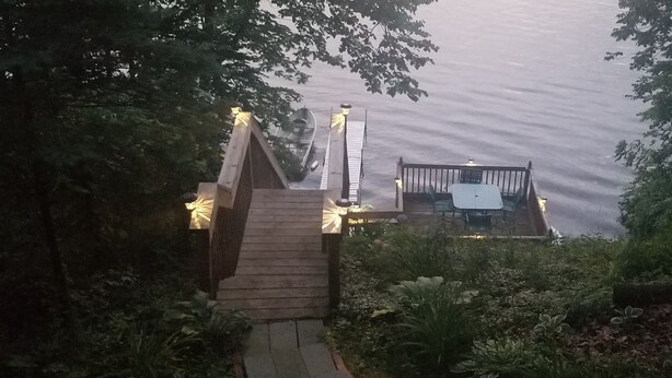 A wooden staircase leading to a dock with boats, surrounded by greenery.