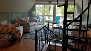 A cozy living room with a sofa, armchair, and a staircase leading to an upper level.
