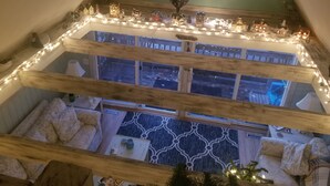 A multi-level room with a sloped ceiling, wooden beams, and a view of the outside.