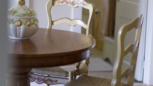 A dining area with a wooden table and two chairs, a decorative bowl on the table, and a hallway in the background.
