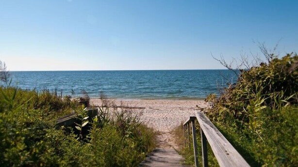A wooden pathway leading to a beach with clear blue water.