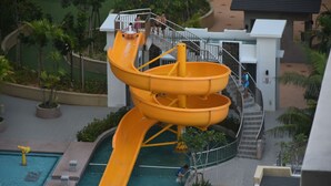 Un parc aquatique doté d’un grand toboggan jaune et d’un espace piscine.
