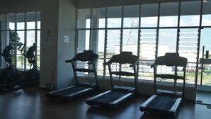 Une salle de sport équipée de tapis de course, de vélos d’appartement et d’un appareil d’aviron.