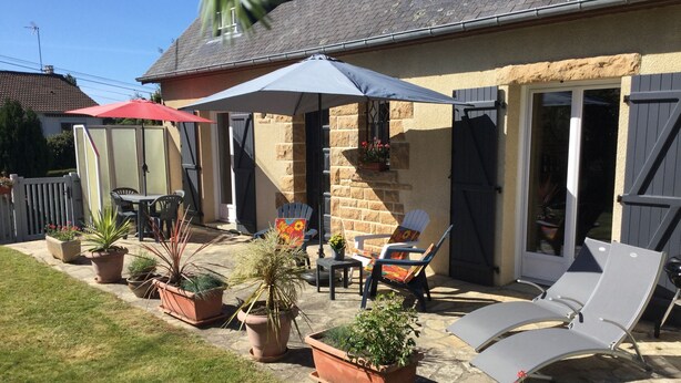 Eine Terrasse mit Gartenmöbeln, Blumentöpfen und einer überdachten Sitzgelegenheit.