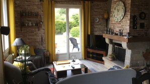 Ein gemütliches Wohnzimmer mit Kamin, Fernseher und einer komfortablen Sitzecke.