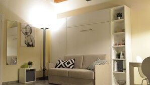 Uma sala de estar moderna com um sofá bege, um abajur, uma estante e um espelho.
