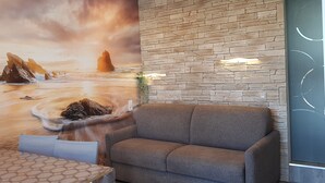 Una habitación con pared de piedra, un sofá y un mural con una playa.