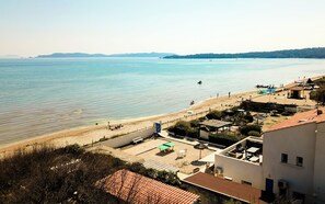 A coastal hotel with a beach view, outdoor seating, and a pool area.